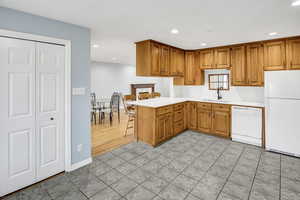 Kitchen with sink, white appliances, kitchen peninsula, and light tile patterned floors