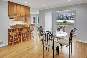 Dining space with ornamental molding and light hardwood / wood-style floors