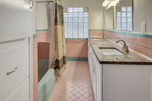 Bathroom featuring shower / bath combination with curtain, vanity, tile walls, and tile patterned floors