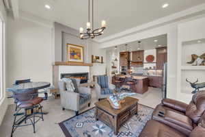 Living room featuring a glass covered fireplace, recessed lighting, an inviting chandelier, and light tile patterned flooring
