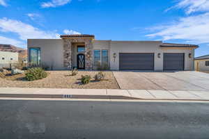 View of front of house with concrete driveway, a tile roof, a garage, and stucco siding