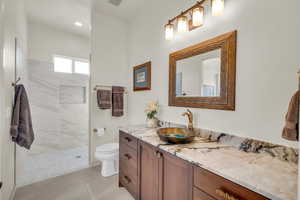 Full bath featuring vanity, tile patterned flooring, visible vents, toilet, and walk in shower