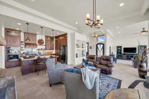 Living room featuring recessed lighting, a raised ceiling, ceiling fan with notable chandelier, and light tile patterned flooring