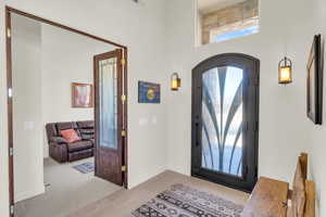 Foyer entrance featuring arched walkways, light tile patterned floors, a towering ceiling, and baseboards