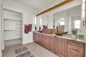 Bathroom with a spacious closet, tile patterned floors, vanity, and baseboards