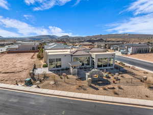 View of front of property with a fenced front yard, stucco siding, a patio, a mountain view, and a residential view
