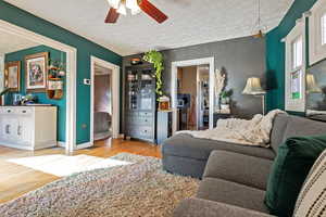 Living room featuring ceiling fan, a textured ceiling, and light wood-type flooring