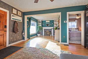 Foyer featuring ceiling fan, a fireplace, light hardwood / wood-style flooring, and a textured ceiling