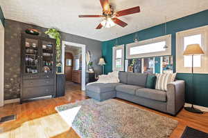 Living room with ceiling fan, hardwood / wood-style flooring, and a textured ceiling