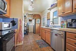 Kitchen with sink, decorative backsplash, light tile patterned flooring, and appliances with stainless steel finishes