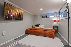 Carpeted bedroom featuring crown molding and a textured ceiling