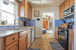 Kitchen featuring tasteful backsplash, sink, light tile patterned floors, and appliances with stainless steel finishes