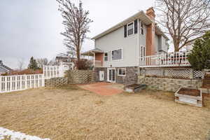 Back of house with a wooden deck, a patio area, and a lawn