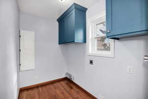 Clothes washing area featuring cabinets, dark wood-type flooring, and hookup for an electric dryer