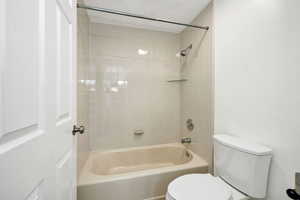 Bathroom with tiled shower / bath and toilet