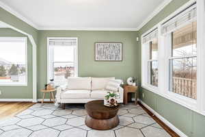 Living area with crown molding and light hardwood / wood-style floors