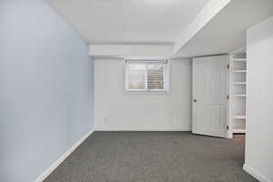 Unfurnished room featuring dark colored carpet and a textured ceiling