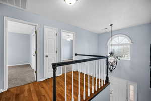 Corridor with wood-type flooring and a chandelier