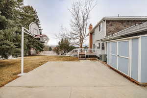 View of patio featuring cooling unit, a storage unit, and a deck