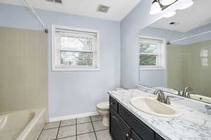 Full bathroom with tile patterned flooring, vanity, tiled shower / bath combo, and toilet