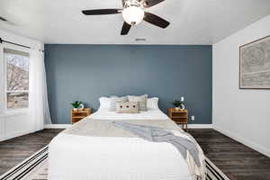 Bedroom with dark wood-type flooring, ceiling fan, and a textured ceiling