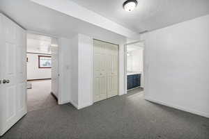 Unfurnished bedroom with a closet, a textured ceiling, and dark colored carpet