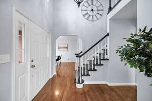 Entrance foyer with dark wood-type flooring and a towering ceiling