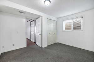 Unfurnished bedroom with a textured ceiling and dark colored carpet