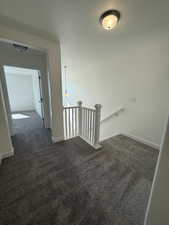 Corridor featuring dark colored carpet, baseboards, and an upstairs landing