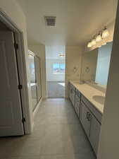 Bathroom featuring visible vents, a sink, a textured ceiling, and double vanity