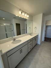 Full bathroom with a stall shower, a sink, a walk in closet, and tile patterned floors