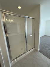 Bathroom with baseboards, a shower stall, and tile patterned floors