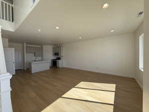 Unfurnished living room featuring baseboards, light wood finished floors, a sink, and recessed lighting