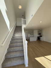 Staircase featuring recessed lighting, a high ceiling, wood finished floors, visible vents, and baseboards