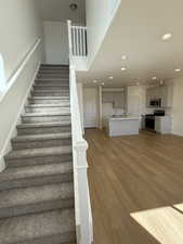 Staircase featuring recessed lighting, a high ceiling, baseboards, and wood finished floors