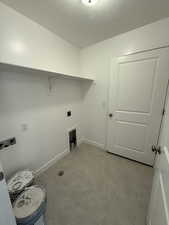 Washroom with light tile patterned floors, hookup for a washing machine, hookup for an electric dryer, laundry area, and baseboards