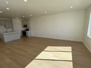 Unfurnished living room with recessed lighting, baseboards, a sink, and light wood finished floors