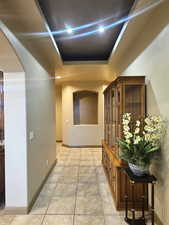 Corridor with a raised ceiling and light tile patterned flooring