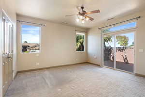 Empty room with visible vents, baseboards, a ceiling fan, and light colored carpet