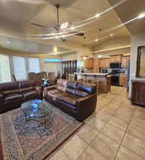 Living room featuring lofted ceiling, ceiling fan, and light tile patterned flooring