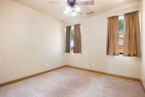 Empty room with visible vents, ceiling fan, baseboards, and a healthy amount of sunlight