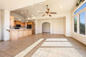 Kitchen featuring a peninsula, light countertops, freestanding refrigerator, a ceiling fan, and arched walkways