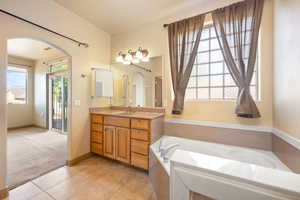 Full bath featuring a garden tub, vanity, baseboards, and tile patterned flooring