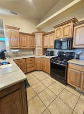 Kitchen featuring light tile patterned flooring, lofted ceiling, sink, and range with gas cooktop