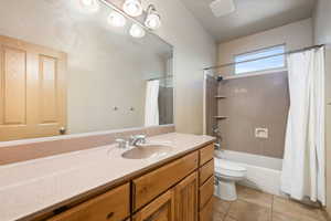 Bathroom with toilet, tile patterned floors, vanity, and shower / bath combination with curtain