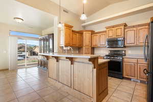 Kitchen featuring light tile patterned floors, a kitchen breakfast bar, a peninsula, visible vents, and stainless steel appliances