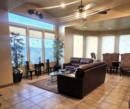 Living room with ceiling fan and light tile patterned flooring