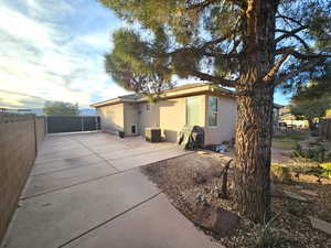 Back house at dusk featuring cooling unit and a patio area