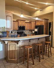 Kitchen with pendant lighting, a breakfast bar area, and black appliances