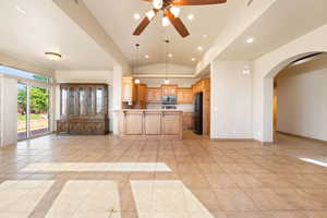 Kitchen with open floor plan, light countertops, stainless steel microwave, and freestanding refrigerator